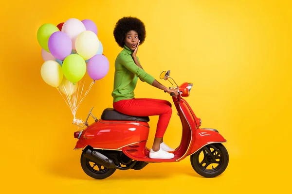 선명 한 노란색 배경에 여러 가지 색깔의 풍선을 단 붉은 자전거를 타고 있는 인상적 인 갈색 피부의 검은 소녀의 사진 — 스톡 사진