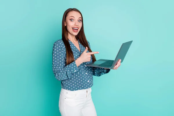 Foto di sorpreso positivo ragazza punto indice dito portatile indossare pantaloni bianchi pantaloni isolati su sfondo color verde acqua — Foto Stock