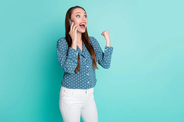 Foto van blij meisje praten op smartphone verhogen vuisten schreeuwen ja geïsoleerd over teal kleur achtergrond — Stockfoto