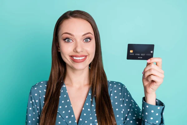 Portré pozitív vidám lány hold hitelkártya viselet kék polka-pont blúz elszigetelt felett türkiz szín háttér — Stock Fotó