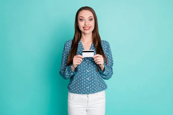 Foto de chica positiva mantenga la tarjeta de crédito use blusa azul pantalones blancos aislados sobre fondo de color verde azulado —  Fotos de Stock