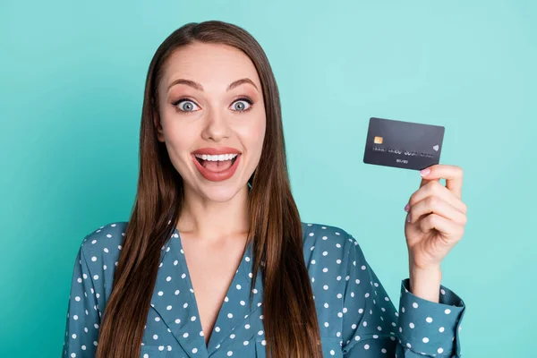 Portret van verbaasd positief meisje houden credit card voor salaris winst slijtage blauwe blouse geïsoleerd op turquoise kleur achtergrond — Stockfoto