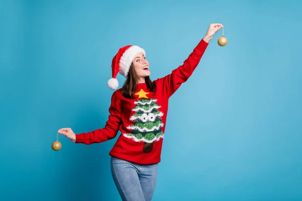 Photo portrait of woman holding two christmas shiny golden baubles isolated on pastel light blue colored background — Stock Photo, Image