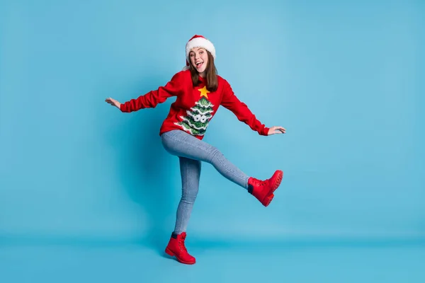 Full body size photo of cute pretty lady raise hands leg flerte girlish open mouth wear santa x-mas headwear red ornamented sweater boots jeans isolated blue color background — Fotografia de Stock