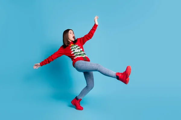 Full body size photo of cute pretty lady stand tiptoe raise hands funny falling open mouth terrified mad look empty space wear red sweater jeans boots isolated blue color background — Fotografia de Stock