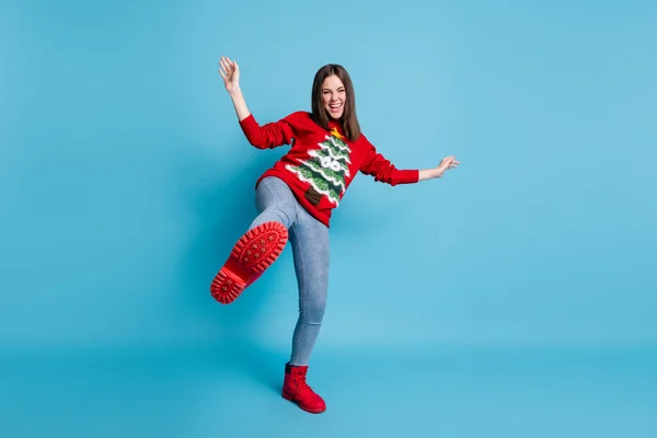 Teljes testhossz fotó vicces demale diák játszik bolondozás álló egyik lábán nevetve mutatja piros cipő visel karácsony pulóver elszigetelt kék színű háttér — Stock Fotó
