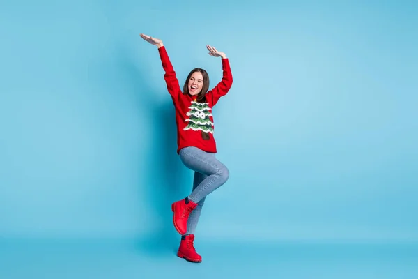 Photo portrait of pretty girl dancing keeping hands up over head wearing red sweater on xmas party isolated on blue color background — Stock Photo, Image