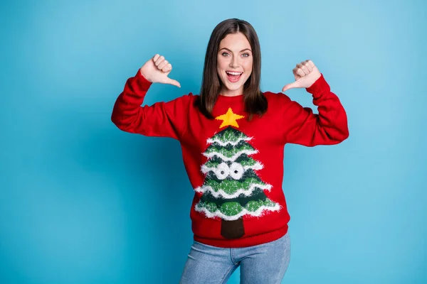 Вибери мене. Фотографічний портрет веселої дівчини, що вказує на великі пальці на себе, посміхаючись у червоному різдвяному пуловері з деревом, зірка в окулярах, ізольована на пастельному світло-блакитному фоні — стокове фото