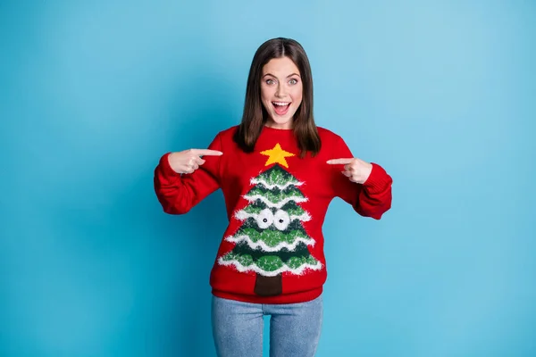 Photo portrait joyful brunette girl pointing fingers at herself surprised shocked smiling wearing red pullover with christmas tree googly eyes star isolated on pastel light blue colored background — Stock Photo, Image