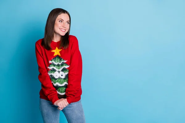 Photo portrait of cheerful brunette woman looking at copyspace holding hands smiling wearing ugly red christmas sweater with tree googly eyes star isolated on pastel light blue colored background — Stock Photo, Image