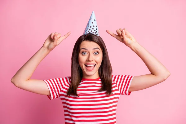 Foto ritratto di allegra ragazza divertente che punta con le dita sul cappello di compleanno sorridente isolato su sfondo rosa pastello — Foto Stock