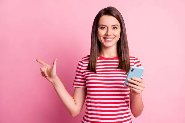 Portrait photo de fille gardant téléphone portable pointant vers l'espace vide isolé sur fond rose pastel — Photo