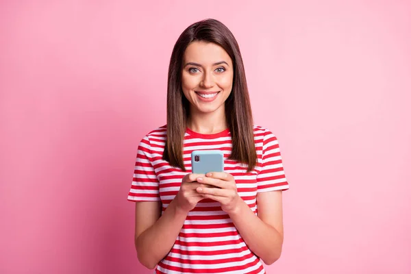 Foto de muito feliz jovem senhora segurar telefone desgaste listrado vermelho branco t-shirt isolado sobre pastel rosa fundo — Fotografia de Stock