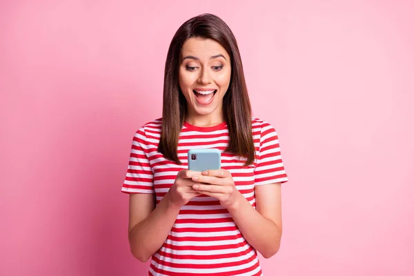 Портрет збудженої дівчини дивиться телефон усміхнений одяг читати білу футболку ізольовано на пастельному рожевому фоні — стокове фото