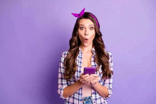 波浪形头发惊讶的女孩拿着手机与紫色背景隔离的照片 — 图库照片