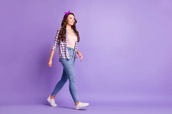 Profilo completo foto di signora camminare spazio vuoto indossare camicia a scacchi retro headband jeans scarpe da ginnastica isolato colore viola sfondo — Foto Stock