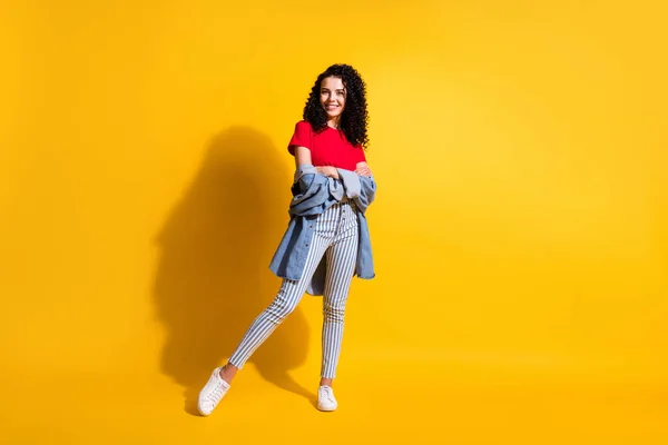 Full längd foto av charmig flicka korsade händer bära randiga jeans röd t-shirt jacka sneakers isolerad gul färg bakgrund — Stockfoto