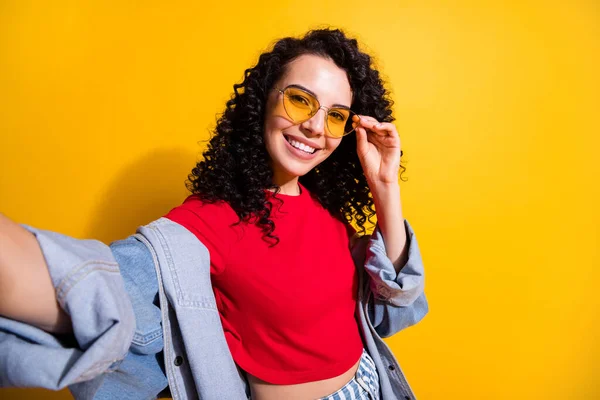 Foto av söt flicka gör skjuta selfie toothy leende bära röd t-shirt jacka solglasögon isolerad gul färg bakgrund — Stockfoto