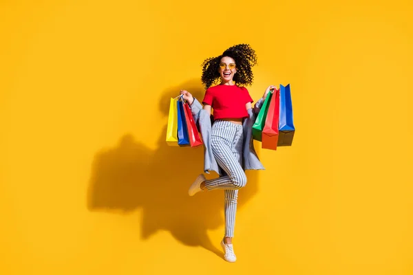 Photo of girl crazy hold store packages wear red t-shirt striped jeans jacket sunglass sneakers isolated yellow color background — Stock Photo, Image