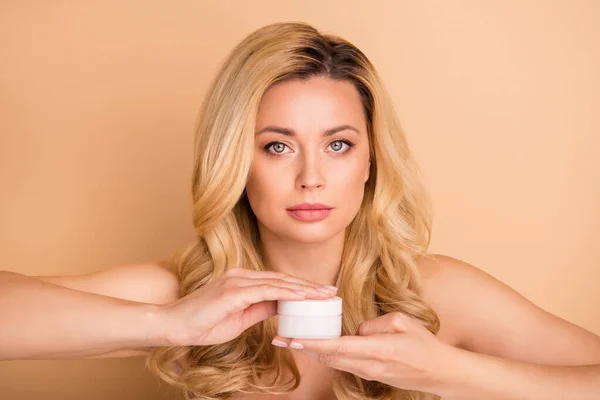 Retrato de cerca de agradable atractivo encantadora dama de pelo ondulado confiado usando nueva crema fresca brillo puro piel impecable elevación efecto botox levantamiento aislado sobre fondo beige — Foto de Stock