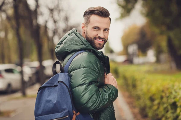 Foto van tevreden bebaarde persoon draai hoofd naar camera tand glimlach goede vibes dragen blauwe tas lopen buiten — Stockfoto