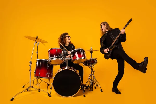 Full size photo of two people famous punk artist man play bass guitar girl drum enjoy recording new composition show wear lather jacket boots isolated bright shine color background