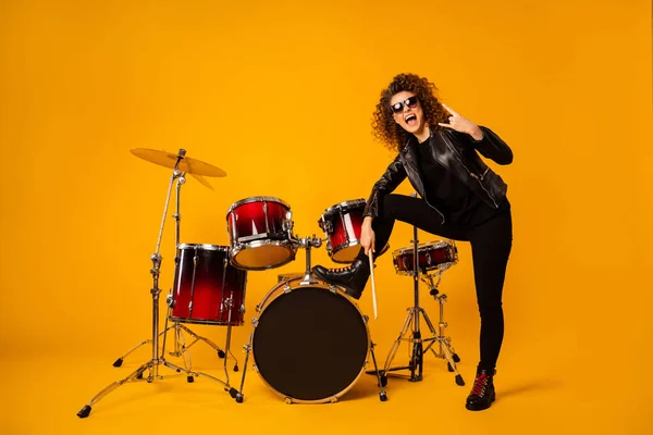 Full body photo of redhair lady stand leg on drum instruments show horns fingers crazy rocker concert performance photographing wear leather jacket sun glasses isolated yellow background — Stock Photo, Image