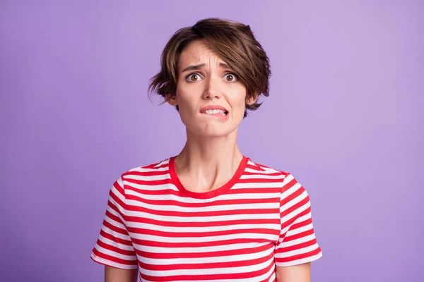 Foto de niña encantadora horrorizada cara mordida labio desgaste rayas camiseta aislado color violeta fondo — Foto de Stock