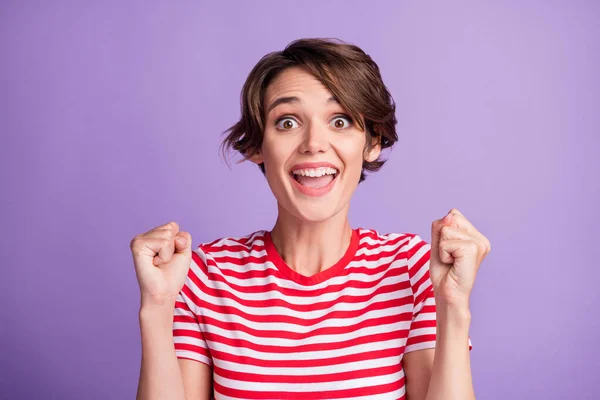 Fénykép aranyos vicces lány nyitott száj emelje öklöt izgatott kopás csíkos póló elszigetelt ibolya szín háttér — Stock Fotó