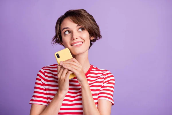 Foto de niña divertida soñadora mantenga el teléfono celular busque espacio vacío use camiseta a rayas aislado color púrpura fondo —  Fotos de Stock