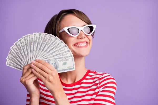현금을 들고 빈 공간을 찾는 젊은 여자의 프로필 사진은 선글라스 줄무늬 티셔츠외진 보라색 배경을 입고 있다 — 스톡 사진