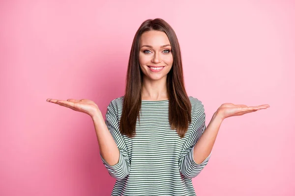 Foto di ragazza positiva due mani tenere vuoto spazio guardare fotocamera sorriso dentato indossare camicia a righe isolato pastello colore rosa sfondo — Foto Stock