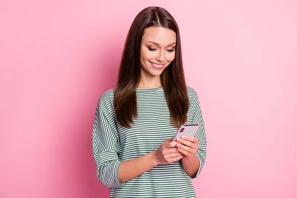 Photo of optimistic sweet young woman stand looking telephone wear cool pullover isolated on pink color background — Stock Photo, Image