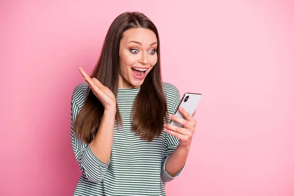 Foto van verbaasd funky jonge dame staan kijken telefoon slijtage pullover geïsoleerd op pastel roze kleur achtergrond — Stockfoto