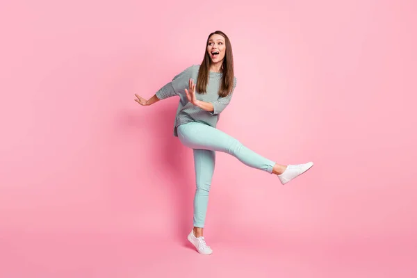 Full size photo of optimistic funky young woman dancing wear shirt blue pants white sneakers isolated on pink color background — Stock Photo, Image