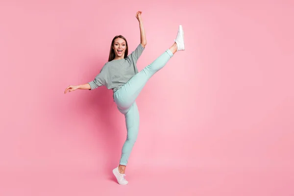 Full size profiel foto van funky mooie jonge dame dansen been up dragen shirt broek sneakers geïsoleerd op pastel roze kleur achtergrond — Stockfoto