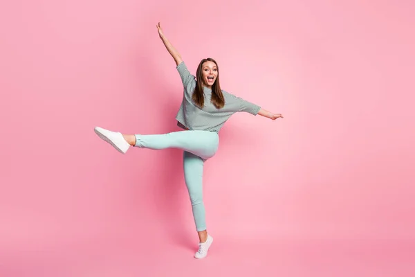 Full storlek profil foto av optimistiska söt ung dam dans ben upp bära skjorta byxor sneakers isolerad på pastell rosa färg bakgrund — Stockfoto