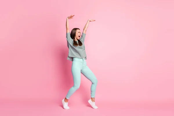 Profil pleine grandeur photo de jolie jeune femme optimiste danse bras vers le haut porter chemise pantalon baskets isolé sur fond rose pastel — Photo