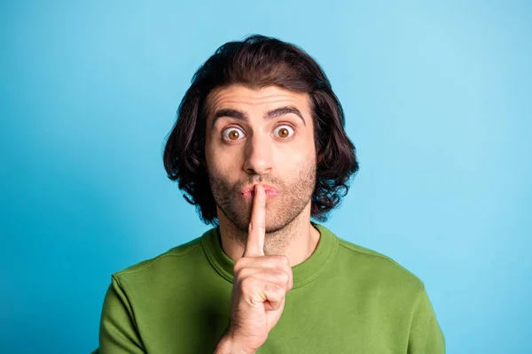 Close up portrait of confused young person show silent sign finger lips green sweater isolated on blue color background — Stock Photo, Image