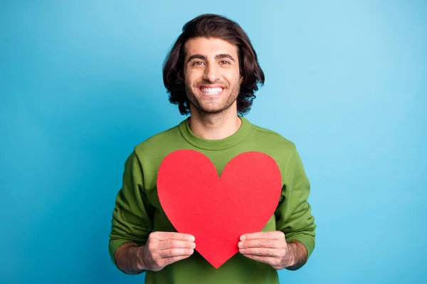 밝은 미소를 짓고 있는 젊은 남자의 사진은 심장에 녹색 도르래를 착용하고 있는 종이를 보여준다. — 스톡 사진