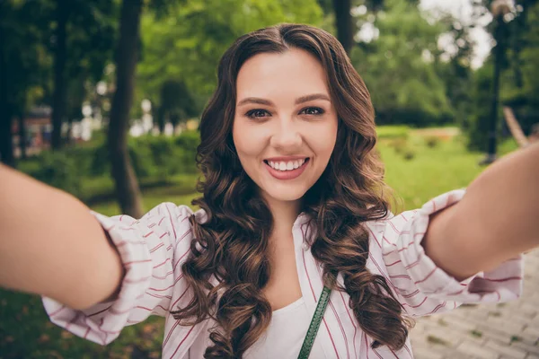 Foto retrato de una chica joven y bonita con el pelo largo y ondulado tomando selfie sonriendo mirando a la cámara en la calle —  Fotos de Stock