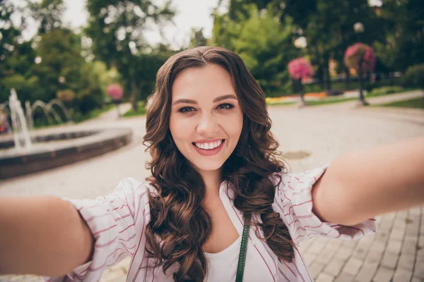 Φωτογραφία πορτρέτο του θηλυκό influencer με μελαχρινή σγουρά μαλλιά λήψη selfie χαμογελώντας φορώντας casual ριγέ πουκάμισο στους δρόμους της πόλης — Φωτογραφία Αρχείου