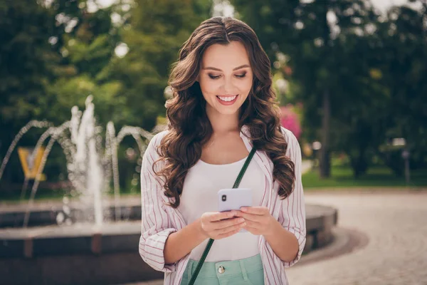 Foto portret van vrouwelijke student typen bericht met behulp van mobiele telefoon glimlachen dragen casual outfit krullend kapsel — Stockfoto