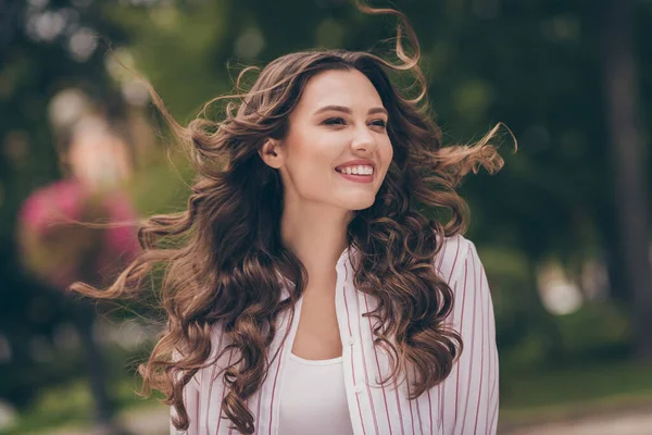 Foto di giovane donna carina ottimista lucido sorridente lunghi capelli ricci camminare parco indossare camicia a righe bianche all'aperto — Foto Stock