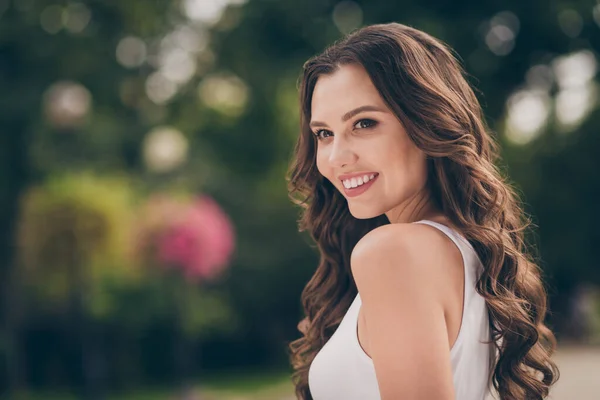 Profilo foto di dolce ottimista giovane signora sorridente lunghi capelli ricci bruna camminare parco indossare top bianco all'aperto — Foto Stock