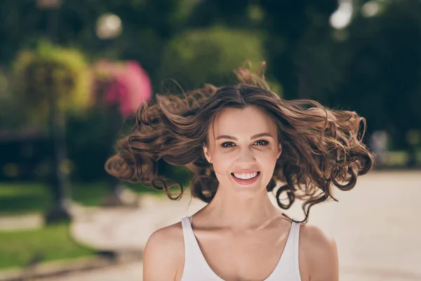 Photo de belle jeune femme mignonne souriant vent dans de longs cheveux bruns bouclés marchant autour porter haut blanc à l'extérieur — Photo