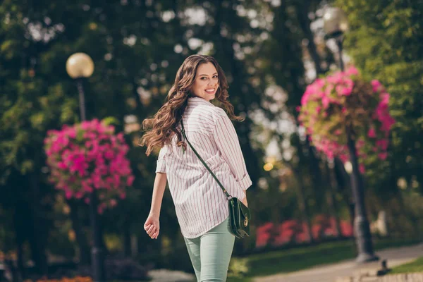 Traseiro atrás vista foto de bonita senhora andar cidade central parque ativo forma vida desgaste verde jeans listrado camisa ombro saco ao ar livre — Fotografia de Stock