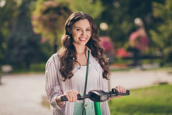 Foto de bonita morena pelo largo joven señora unidad segway usar camisa rayada disfrutar de caminar en el parque al aire libre —  Fotos de Stock