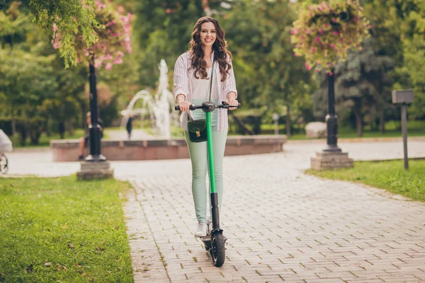 Foto de cuerpo completo de la bonita joven sonrisa feliz disfrutar de paseo scooter eléctrico primavera en el parque —  Fotos de Stock