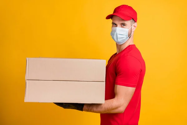 Профіль фотографії доставки чоловіка тримає два великих пакети одягу маски червона футболка шапка ізольовані жовтого кольору фону — стокове фото
